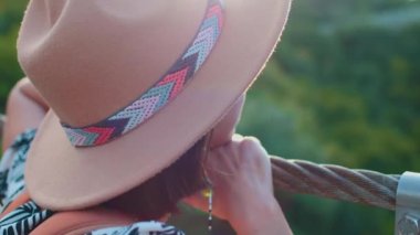 Asma köprüde duran şapkalı genç bir kızın portresi. Yüzün yakın plan görüntüsü.