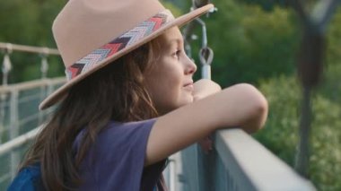 Kendine güvenen bir çocuğun portresi. Şapkalı bir çocuk köprüde duruyor ve hayaller kuruyor. macera ve seyahat.
