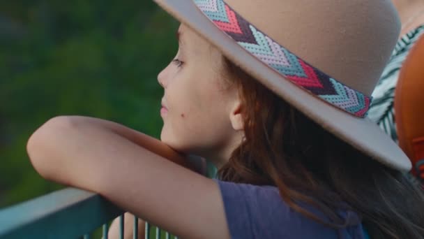 母親は優しく子供を抱きしめている 手を閉じる 帽子をかぶった少年が橋の上に立って自然を眺める ファミリーウォーク — ストック動画