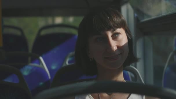 笑顔の若い女性が公共バスに乗っている バスに乗った少女 — ストック動画