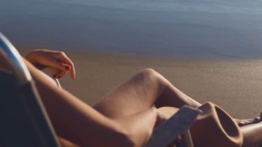 Yaz plajı tatili konsepti. Genç kız elinde şapkasıyla güneşlenip dinleniyor..