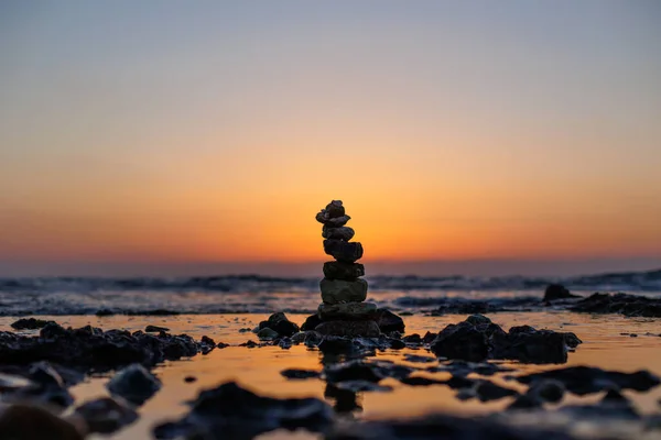 Stone balance on the beach at sunset. Pyramid of the small pebbles on the beach. Stones, against the background of the sea shore during sunset