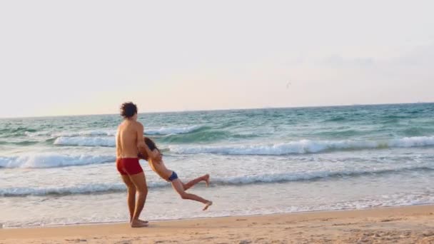 幸せな父親と息子がビーチで一緒に遊んでいました 父親は息子を回して 手を握った フリーで幸せな陽気なライフスタイル — ストック動画