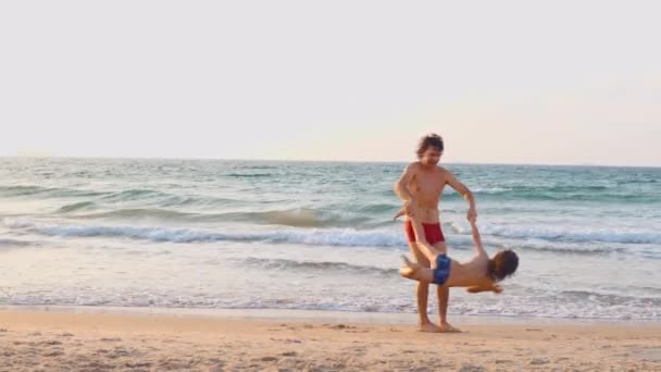 快乐的父亲和儿子一起在海滩上玩耍 爸爸牵着他的手 扭动着他的儿子 无忧无虑快乐的生活方式 — 图库视频影像