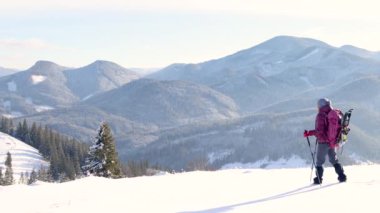 Kış yürüyüşü. Sırt çantalı ve kar ayakkabılı bir kadın dağlarda karda yürür, kış yürüyüşü yapar, kışın dağlarda yürüyüş malzemesi yürür.