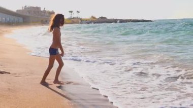 Mutlu bir çocuk denize koşar. Okyanus sahilinde bir çocuk oynuyor. Gün batımında bir çocuk dalgalara atlıyor. Çocuklu aileler için deniz tatili. Küçük bir çocuk tropik bir plaj boyunca koşar..