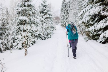 Kış aktivitesi. Karda kar ayakkabılarıyla yürüyen iki kadın, kış yürüyüşü yapan iki kişi, kışın dağlarda yürüyüş yapan iki kişi.