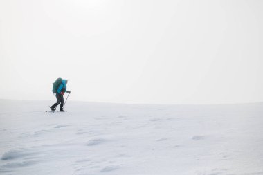 Dağlara tırmanan. Bir kız dağlarda karda yürür. Kar üzerinde kar ayakkabıları.