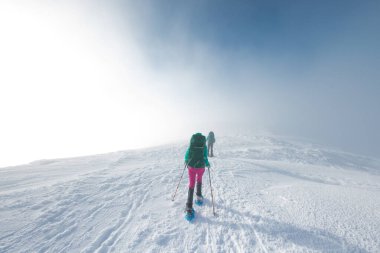 Kış dağlarında kar ayakkabılı iki turist. Dağlarda macera..