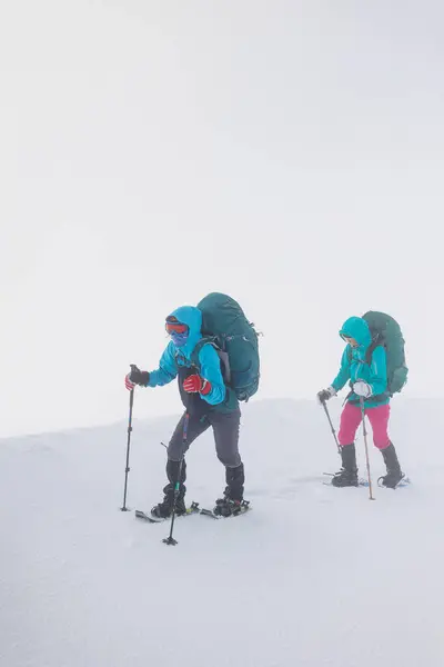 climbers climb the mountain. Winter mountaineering. two girls in snowshoes walk through the snow. hiking in the mountains in winter.