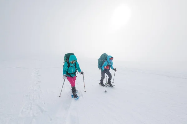 climbers climb the mountain. Winter mountaineering. two girls in snowshoes walk through the snow. hiking in the mountains in winter.
