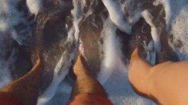 Romantik genç bir çift sahilde durur ve dalgaların ayaklarına dokunuşunu izler. İnsanlar deniz kenarında aşk ve romantizmden hoşlanırlar. Yaz tatilindeki çift..