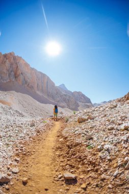 Çocuk sırt çantasıyla dağlarda geziyor. Yüksek dağlarda dağ yürüyüşü. Çocuk bir dağ yolunda yürüyor. Türkiye.