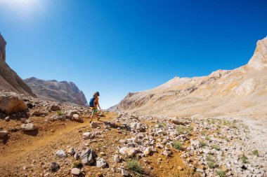 Çocuk sırt çantasıyla dağlarda geziyor. Yüksek dağlarda dağ yürüyüşü. Çocuk bir dağ yolunda yürüyor. Türkiye.