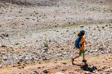 Sırt çantalı çocuk dağ yolunda yürüyor. Çocuk bir sırt çantasıyla dağlara seyahat ediyor. Yüksek dağlarda dağ yürüyüşü. Türkiye.