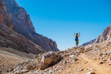 Sırt çantalı küçük bir çocuk dağın arka planına karşı yol boyunca ayakta duruyor. Seyahat ve yürüyüş. Çocuklarla dağlara git. Hindi. Aladaglar.