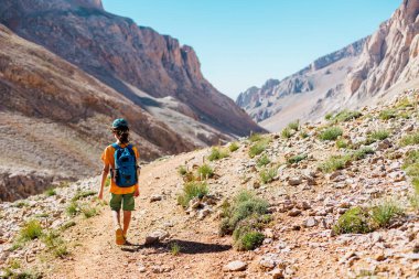 Sırt çantalı çocuk dağ yolunda yürüyor. Çocuk bir sırt çantasıyla dağlara seyahat ediyor. Yüksek dağlarda dağ yürüyüşü. Türkiye.
