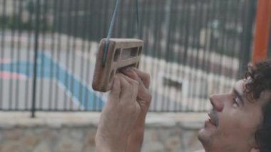 Kaya tırmanışçısı bir klavye üzerinde egzersiz yapıyor. Güçlü bir erkek kaya tırmanıcısının eli, parmak gücünü eğitmek için bir tahta tutar. Kaya tırmanışı eğitimi. Güç ve dayanıklılık. pano ve askı.