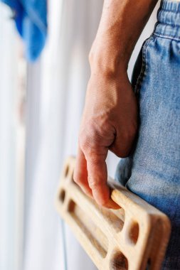 Kaya tırmanışçısının güçlü erkek eli, parmak eğitimi için bir tahta tutuyor. Evde tırmanma egzersizi. Kaya tırmanışçısının eli yakın çekim. Güç ve dayanıklılık. klavye ve askı