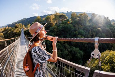Şapkalı genç kız asma köprüde duruyor ve hayallerindeki uzaklığa bakıyor. yakın plan.