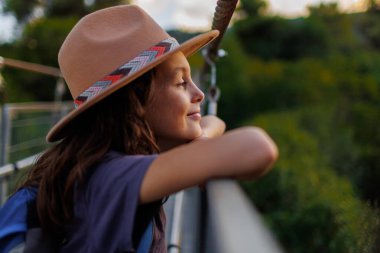 Kendine güvenen bir çocuğun portresi. Şapkalı bir çocuk köprüde duruyor. macera ve seyahat.