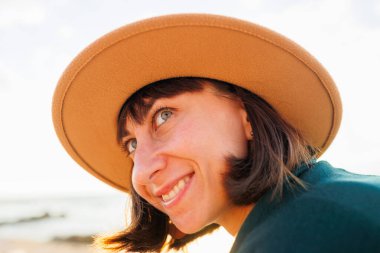 Şapkalı genç bir kızın portresi. Deniz kenarında akşam yürüyüşü. deniz kenarında tatil.