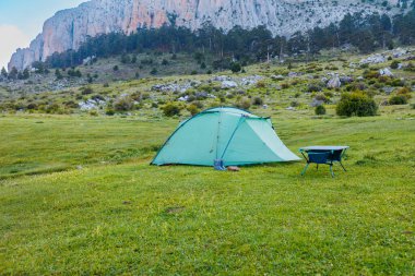 Yeşil bir kamp çadırı arka planda güzel dağlar olan yeşil bir çayırda duruyor. Dışarıda vakit geçirmek. Seyahat ve kamp konsepti. Dedegol. Türkiye.