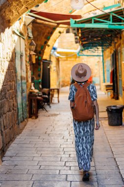 İsrail 'in tarihi Acre şehrini keşfeden şapkalı ve sırt çantalı güzel bir gezgin kız. seyahat ve macera