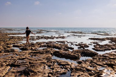Kız kayalık bir plaj boyunca yürüyor. Deniz boyunca yürü. # Kız deniz kenarında yürüyüş yapıyor #.