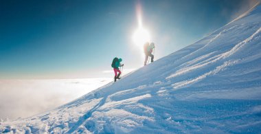 Dağcılar karda dağa tırmanırlar. Kış dağcılığı. Kar ayakkabılı iki kız karda yürür. Dağcılık ekipmanları. Kışın dağlarda yürüyüş..