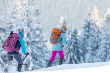 Kış dağları. Kar ayakkabılı ve sırt çantalı iki kişi yürüyüşe çıktı. Macera ve aşırı eğlence kavramı..