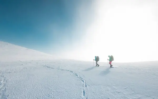 two girls walk along a mountain path in snowshoes. walking in the snow. hiking in the mountains in winter.