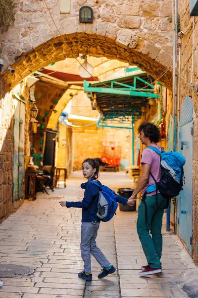 Happy tourists, father and son with backpacks, against the backdrop of an old street. Travel concept with children. a male tourist walks through the old town with his son.