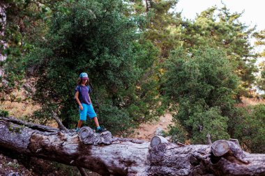 Çocuk ormanda devrilmiş bir ağacın üzerinde yürüyor. Çocukların eğlencesi, mutlu bir çocuk ağaca tırmanıyor ve eğleniyor. Bir çocukla yürümek..