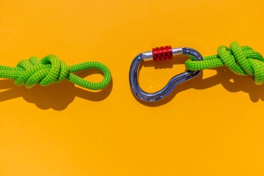 rope with a secure knot and a carabiner lies on a colored background. Equipment for rock climbing and mountaineering. reliable connection. Safety rope. concept of reliability and strength.