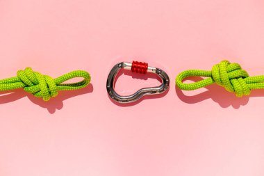 rope with a secure knot and a carabiner lies on a colored background. Equipment for rock climbing and mountaineering. reliable connection. Safety rope. concept of reliability and strength.