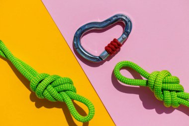 carabiner with a rope lies on a colored background. Equipment for climbing and mountaineering. reliable connection. Safety rope.  the concept of reliability and strength. copy space.