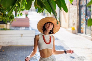 Şapka ve boncuklu genç bir kızın portresi. Modaya uygun aksesuarlar. Model kameraya bakar ve gülümser..