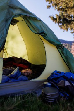 Çocuk bir çadırda uyuyor. Çocuk uyku tulumunda uyuyor. Bir çocukla dağlarda yürüyüş yapmak. etkin yaşam biçimi.