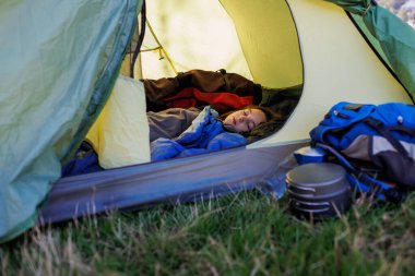 Çocuk bir çadırda uyuyor. Çocuk uyku tulumunda uyuyor. Bir çocukla dağlarda yürüyüş yapmak. etkin yaşam biçimi.