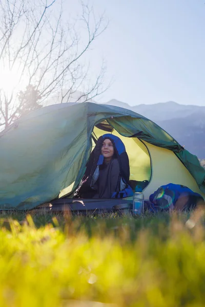 happy smiling child sitting in a tent against the backdrop of the mountains. baby in a sleeping bag. portrait of a child in a tent. children's outdoor recreation. camping and trekking with children.