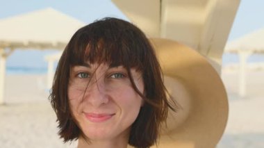 Sahilde tatilin tadını çıkaran hoş bir kız. Kumsalda gülümseyen genç ve mutlu bir kadın. Kız yolculuğun tadını çıkarıyor..
