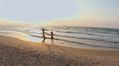 Mutlu genç anne ve oğlu sahilde birlikte gülüp eğleniyorlar. Çocuğu olan genç bir anne. Sahilde aile tatili. Aile gezisi.