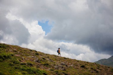 Çocuk sırt çantasıyla dağlardaki bulutların arkasına gidiyor. Sırt çantalı çocuk gezgini, yürüyüş, seyahat, yaşam tarzı konsepti