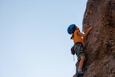 Dağcı çocuk. Çocuk kaya tırmanışı eğitimi alıyor. Doğada spor. Sevimli genç çocuk sigorta ile kayaya tırmanıyor, yaşam tarzı spor insanları buna katılıyor.