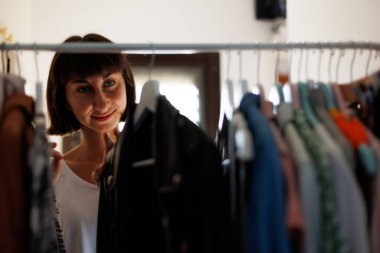 Evde gardırop ya da giyim mağazasının soyunma odası. Genç bir kadın evdeki ya da mağazadaki dolabından şık bir kıyafet seçer. Kız ne giyeceğini düşünüyor..