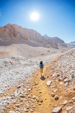 Çocuk sırt çantasıyla dağlarda geziyor. Yüksek dağlarda dağ yürüyüşü. Çocuk bir dağ yolunda yürüyor. Türkiye.