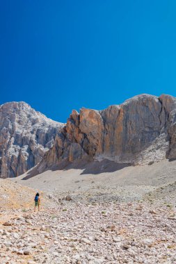 Çocuk sırt çantasıyla dağlarda geziyor. Yüksek dağlarda dağ yürüyüşü. Çocuk bir dağ yolunda yürüyor. Türkiye.
