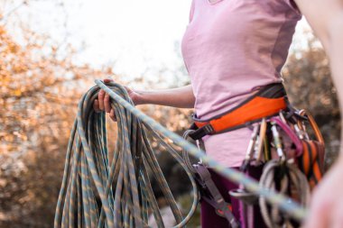 Tırmandıktan sonra ipe tırmanan biri. Kaya tırmanıcısının koşum takımı ve tırmanma ekipmanlarıyla yakın çekimi. Yükseklik ve kaya tırmanışı