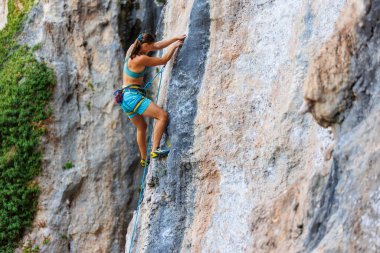 Genç ve güçlü bir kadın kayaya tırmanıyor. Güç ve dayanıklılık.